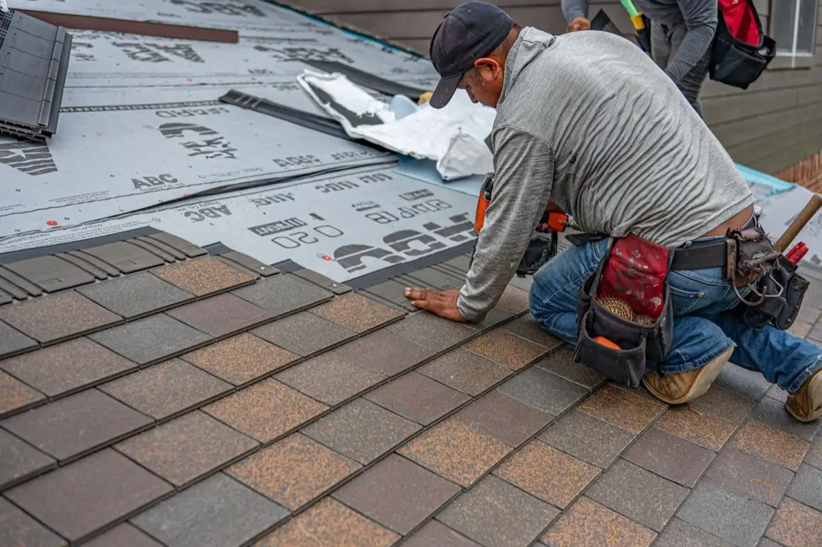 Roofing installer fastening shingles over new underlayment in Miami Gardens, FL